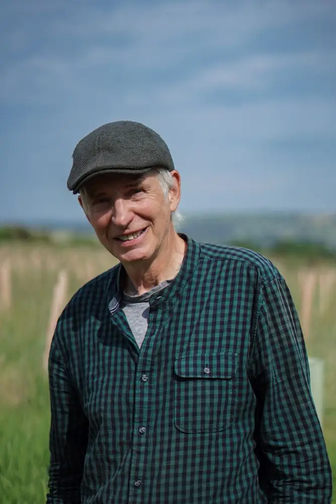 A man wearing tartan smiling and looking at the camera in a flat peak cap | Microsite | Microsite
